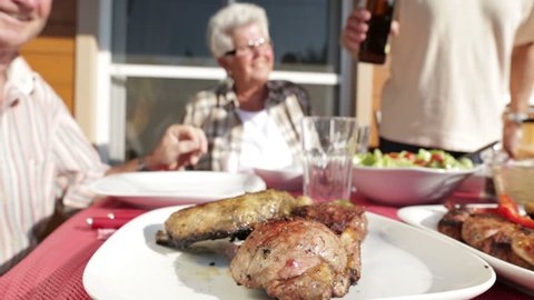 dolly shot seniors at barbecue table with beer outdoors on terrace
