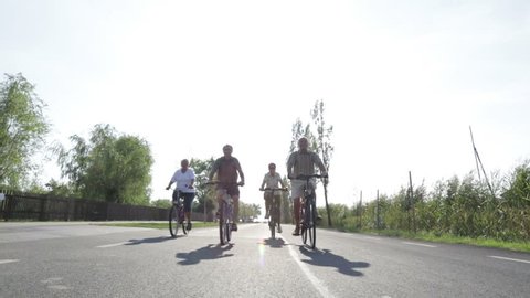 four retirees biking on road in summer

