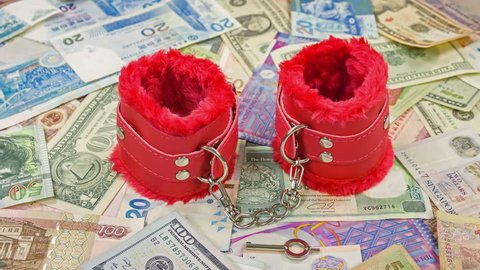 Handcuffs red with red faux fur lining leather on the world money. Close up.
