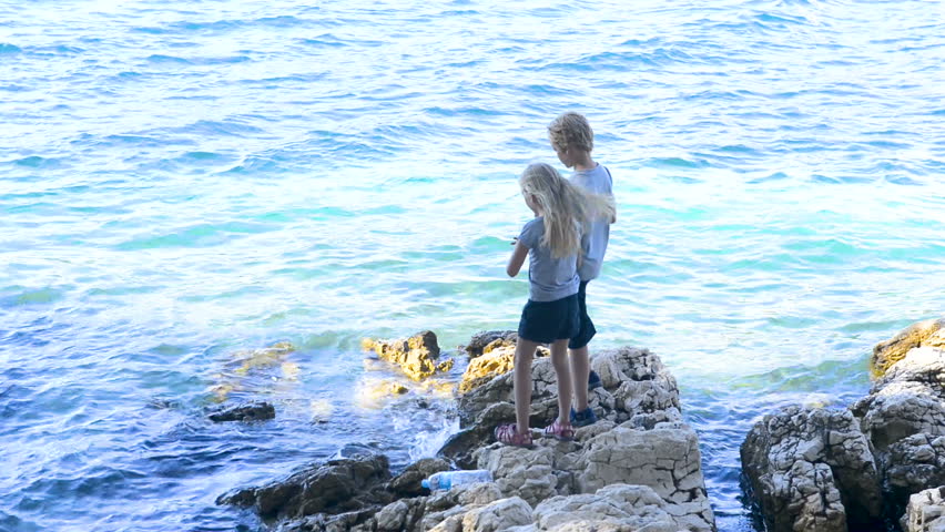 Children boy and girl playing on rocky beach in Hvar harbor, Croatia