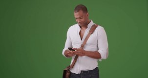 A young black man records video on his mobile phone on green screen. On green screen to be keyed or composited.