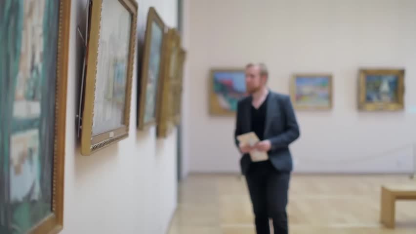 Man in a Suit Looks at a Picture in a Museum