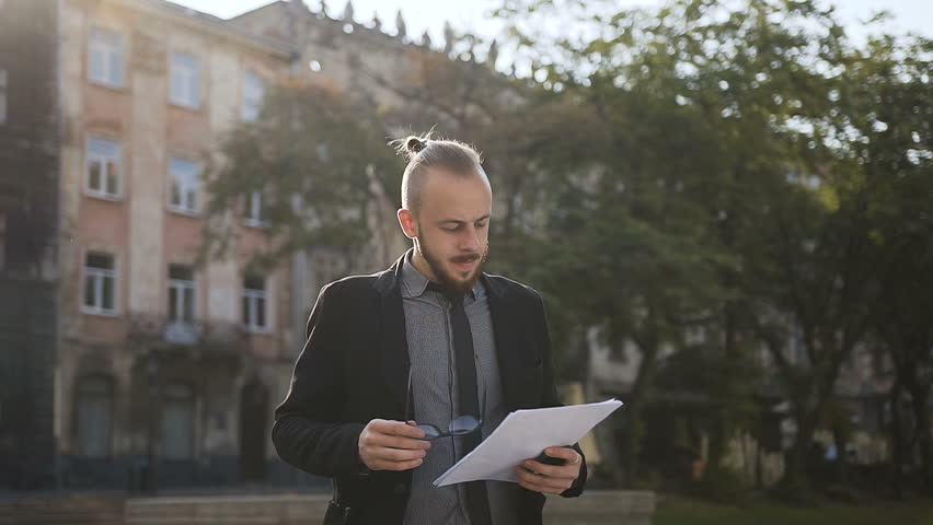 A young man in his glasses holds documents in his hand slow motion