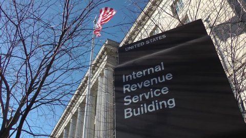 Internal Revenue Service - IRS - headquarters in Washington, DC. Sign with American flag flying above.