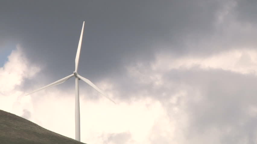 Wind turbine spinning along hillside in Washington on cloudy day.