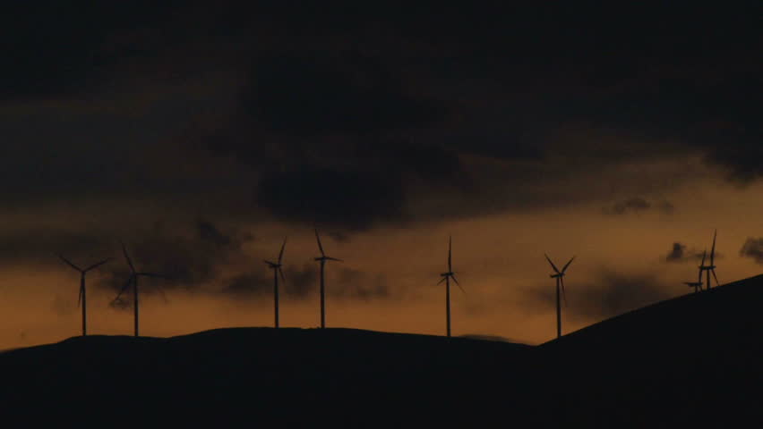 Wind turbines spinning along hillside in Washington at sunset, time lapse.