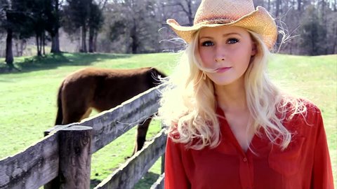 Cowgirl walks down a fence line. slow motion.  Stock Video