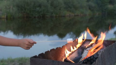 Marshmallows on camping fire. camping, travel, tourism, hike and people concept - happy family roasting marshmallow over campfire. marshmallow on skewers. marshmallows on stick over the bonfire