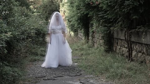 The ghost of the bride wanders through the ruins of the old castle. Bride of the Zombie. 4 k. Slow-motion shooting