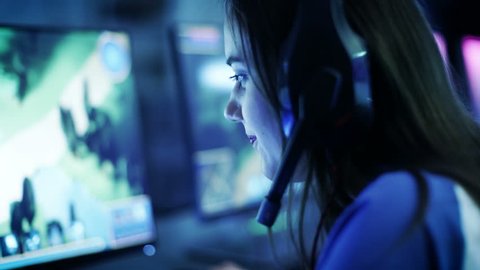 Professional Girl Gamer Plays in MMORPG/ Strategy Video Game on Her Computer. She's Participating in Online Cyber Games Tournament, or in Internet Cafe. She Wears Gaming Headphones. 4K UHD.