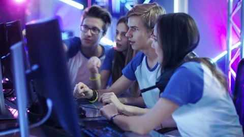 Team of Professional Boys and Girls Gamers Actively Thinking/ Discussing Game Strategy/ Tactic, They're In Internet Cafe or on Cyber Games Tournament. Shot on RED EPIC-W 8K Helium Cinema Camera.