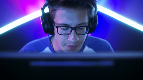 Professional Gamer Plays in MMORPG/ Strategy/ Shooter Video Game on His Computer. He's Participating in Online Cyber Games Tournament, Plays at Home, or in Internet Cafe. He Wears Glasses and Headset.