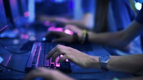 Close-up On Row of Gamer's Hands on a Keyboards, Actively Pushing Buttons, Playing MMO Games Online. Background is Lit with Neon Lights. Shot on RED EPIC-W 8K Helium Cinema Camera.