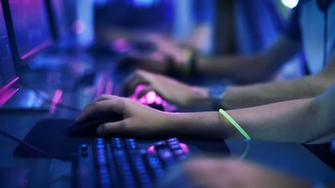 Close-up On Row of Gamer's Hands on a Keyboards, Actively Pushing Buttons, Playing MMO Games Online. Background is Lit with Neon Lights. Shot on RED EPIC-W 8K Helium Cinema Camera.