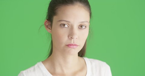 Beautiful millennial girl modeled for camera isolated on greenscreen background. Close-up of White woman looking at camera on Chroma key.