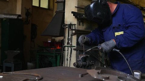 Man welds iron in a mask.