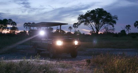 Tourists on game drive vehicle at night looking for animals in the bush