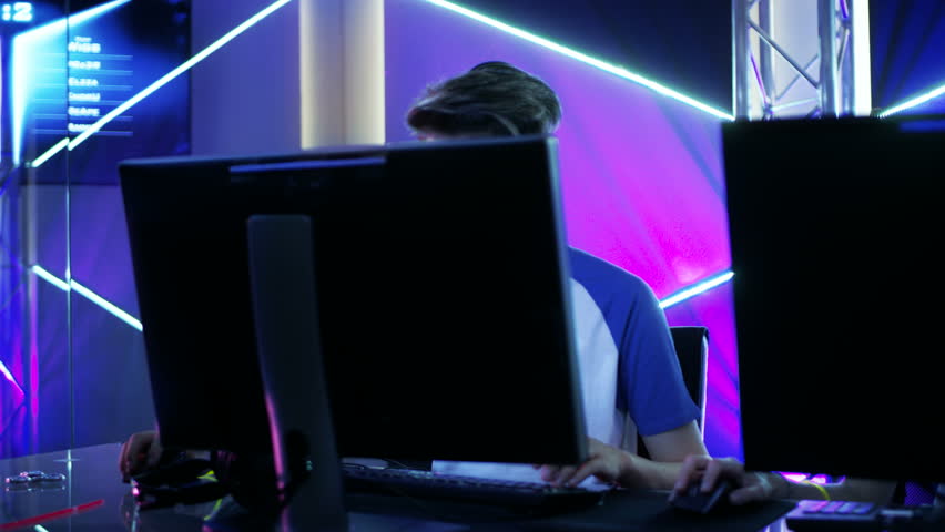 Moving Shot of Team of Teenage Gamers Playing in Multiplayer PC Video Game on a eSport Tournament. Emotionally Charged Moment.