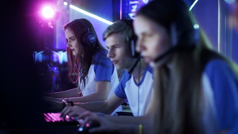Depth of Field Shot of Team of Teenage Gamers Playing in Multiplayer PC Video Game on a eSport Tournament. They Speak in Microphones. Emotional Gaming Moment.Shot on RED EPIC-W 8K Helium Cinema Camera