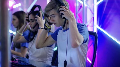 Team of Teenage Gamers Get Ready for eSport Tournament, Put on Their Headsets. Tournament Area/ Internet Cafe Looks Cool with Neon Lights. Shot on RED EPIC-W 8K Helium Cinema Camera.