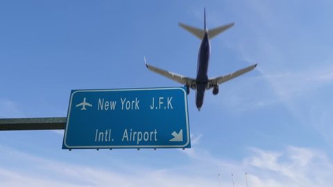 new york airport sign airplane passing overhead