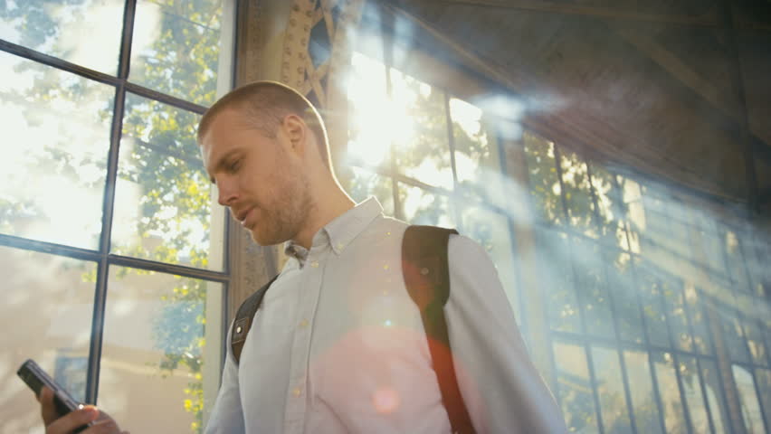 Man using mobile phone on empty railway platform. Shot in Red Epic Dragon