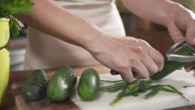 Chef peels cucumbers for making vegetable salad with fresh greens, vegetarian dishes, cooking food, healthy nutrition