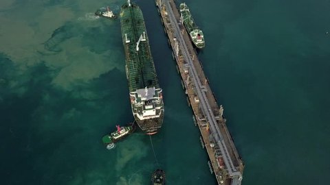 Aerial view Crude oil tanker under cargo operations on typical shore station with clearly visible mechanical loading arms and pipeline infrastructure. Thailand harbor.