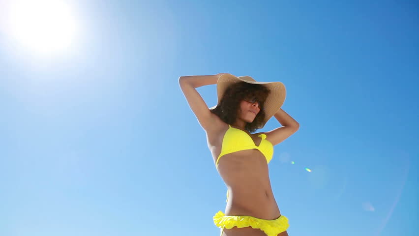 Woman in a yellow bikini dancing at the beach
