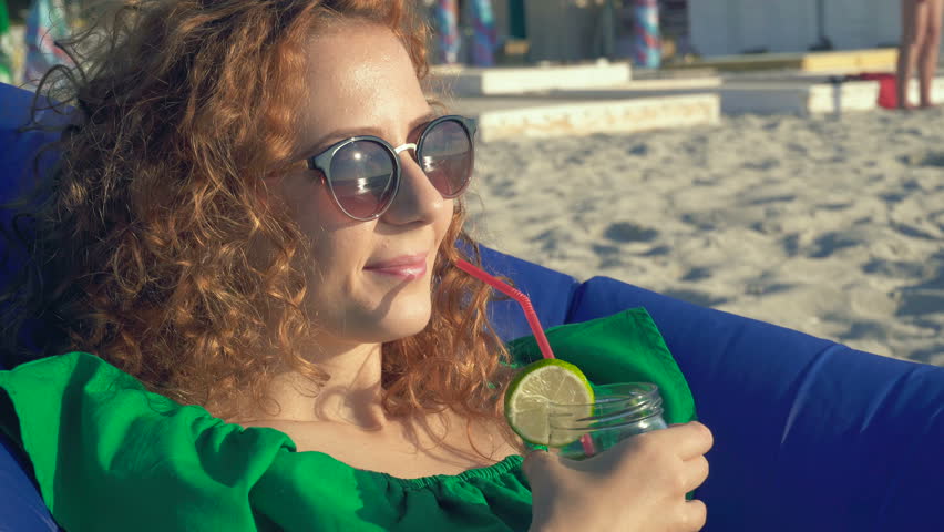 Young woman enjoying a tropical mojito cocktail with fresh lime at the seaside