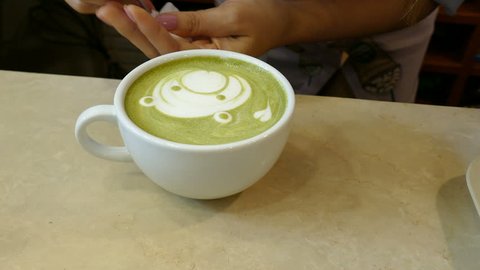 barista making bear face and heart shape latte art on hot matcha green tea in café coffee shop
