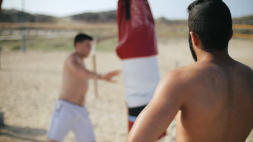 Sporty man looking at boxing training. Boxer making strikes on combat bag