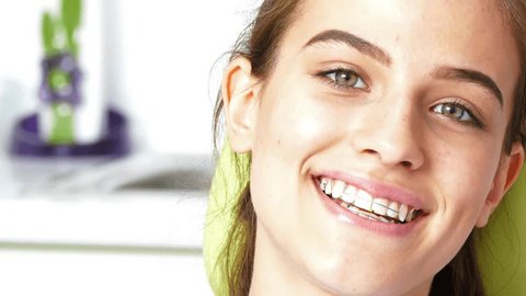 Portrait of smiling young girl with a braces in the mouth in the dentist office