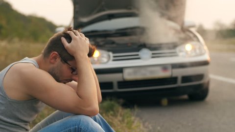 Man sitting in a front of broken car