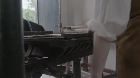 VIRGINIA - SPRING 2016 - Re-enactment recreation of historical, 18th or 19th century Printing Press at work with male Printer working the levers, wheels and print type / ink. Printing Newspapers. 4K