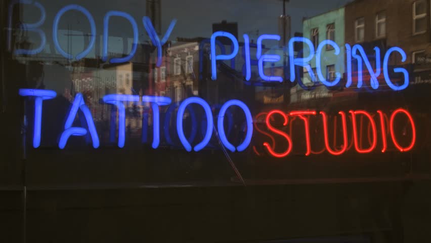 Body piercing and tattoo studio neon sign seen on the e Camden market in London, United Kingdom