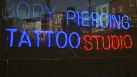 Body piercing and tattoo studio neon sign seen on the e Camden market in London, United Kingdom