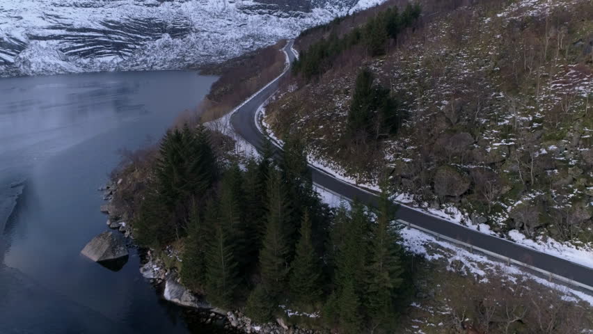 Aerial view following car driving on road next to lake in Norway