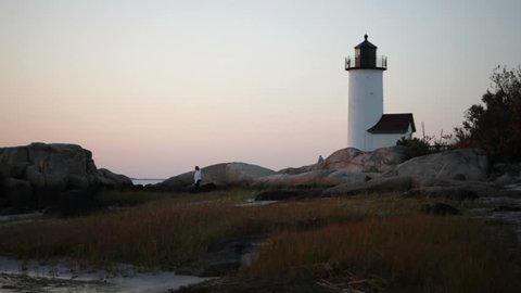 Cape Ann lighthouse at sunset with couple and dog