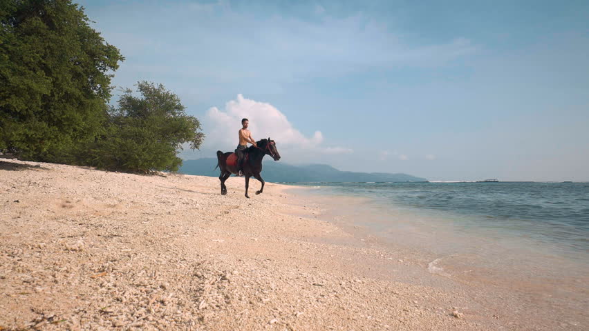 Indonesian man riding horse on beach