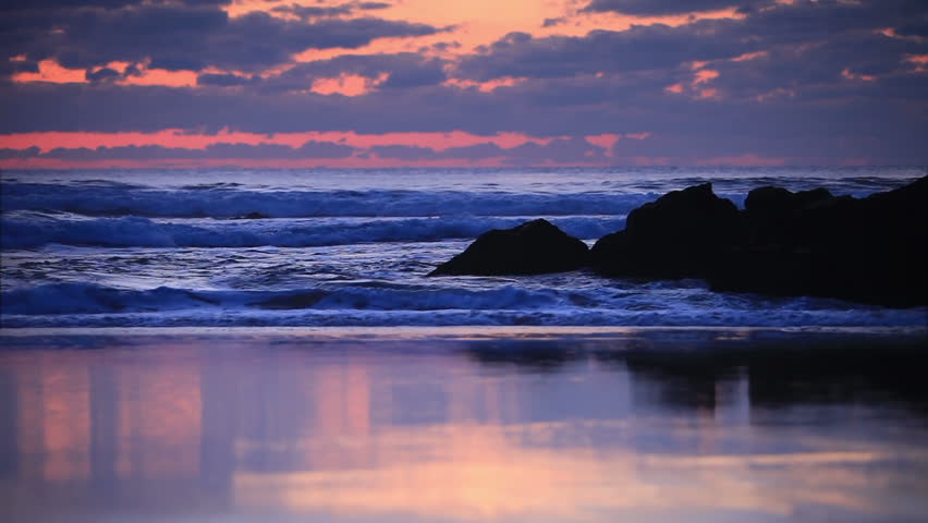Bright sunset, surf wave and rock on shore
