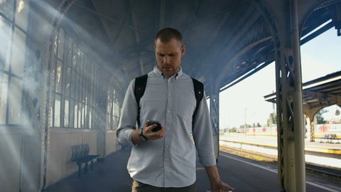 Young man walking with suitcase and looking at phone. Shot in Red Epic Dragon