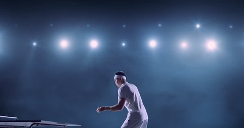 Ping pong player in action on a professional sports arena. He is wearing unbranded clothes. 