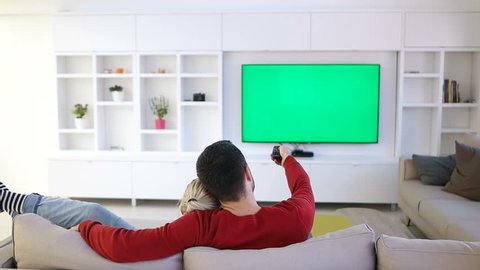 couple relaxing and watching tv in modern apartment