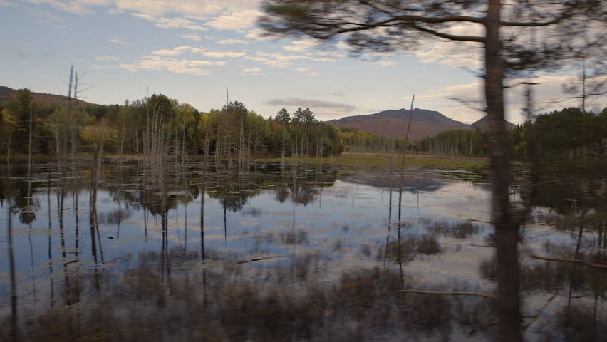Moving pan shot of sunrise over a lake in the Adirondack Mountains.