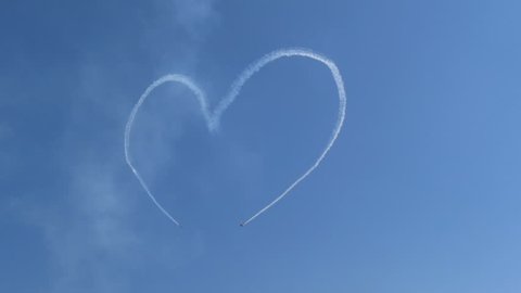 MOSCOW, RUSSIA July 21, 2017: jet military airplanes draw heart symbol with aircraft exhaust fumes in bright clear blue sky at airshow