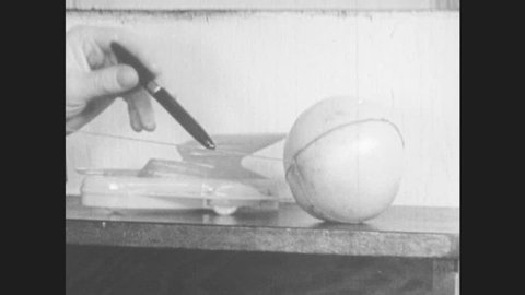 1950s: man in suit points with pen, carries rocketship model across string from grapefruit to golfball, talks, turns on 16mm movie projector and turns off lights in office as boy watches.
