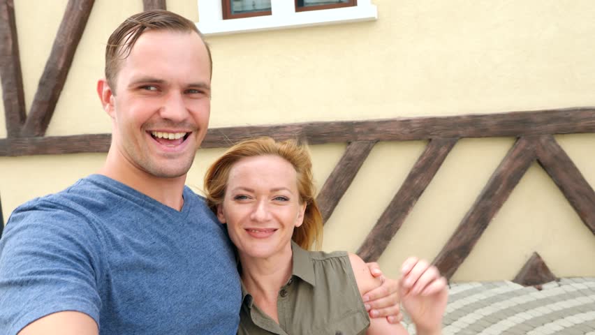 Happy couple of tourists photographing a selfie in a city street in a sunny day. 4k, slow motion.