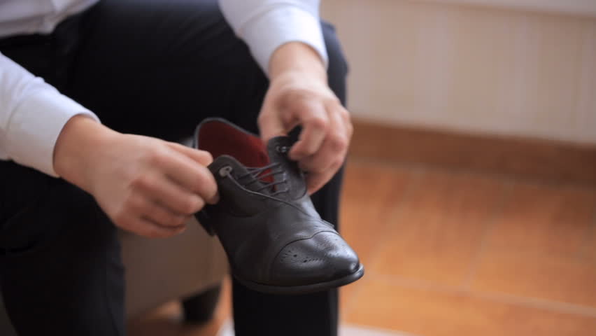 Man puts on shoes. man puts on black new fashion shoes and tie shoelaces. close-up