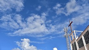 time-lapse video of of radio tower and red cross with blue sky background.